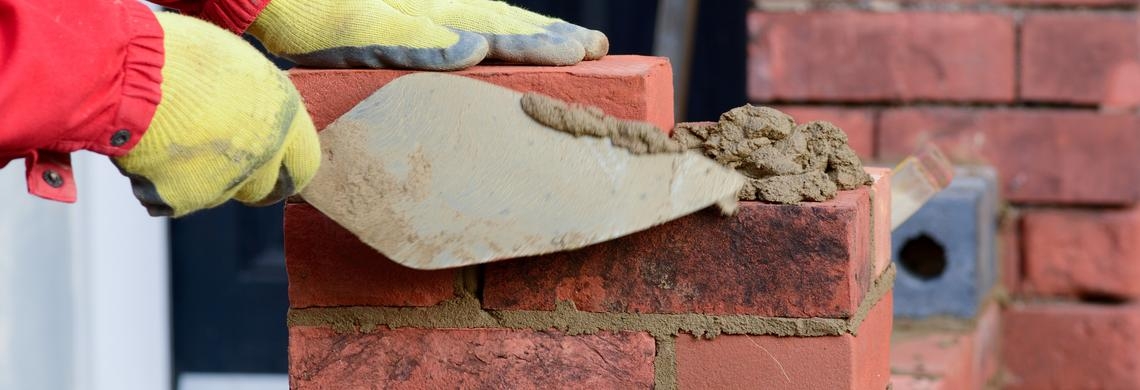 Ein Mensch erstellt eine Mauer aus Backsteinen